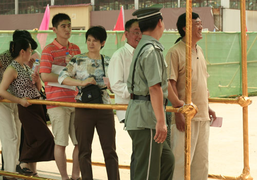 A security man talks with residents at the venue for a vote on demolishment and reconstruction of old buildings in Juixiaqiao Sub-district in Beijing, June 9, 2007. Local government and the real estate developer jointly organize the vote on Saturday to see if majority residents of over 5000 families accept the new compensation policy after failed attempts to reach an agreement through other ways. Both notary officials and supervisors are invited to monitor the vote that runs from 9 a.m. to 9 p.m. at six ballot booths. [Sun Yuqing/y3k9.com]