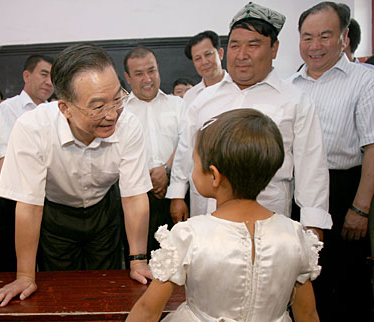 Chinese Premier Wen Jiabao (L) talks with a student at a bilingual kindergarten during his inspection tour to the northwestern Xinjiang Uygur Autonomous Region from last Thursday to Sunday. Wen Jiabao visited villages, schools, enterprises, hospitals and the Xinjiang production and construction corps of the army in a number of prefectures and cities to show his extensive care for local people's livelihood, education, medical service and the development of energy sources，Xinhua reported.Picture taken on August 16.[Xinhua]