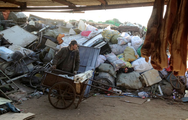 A garbage sorter at the Dongxiaokou garbage recycling market in Beijing transport recyclable waste on Jan 1. Zheng Xin / China Daily Garbage recyclers make way for real estate