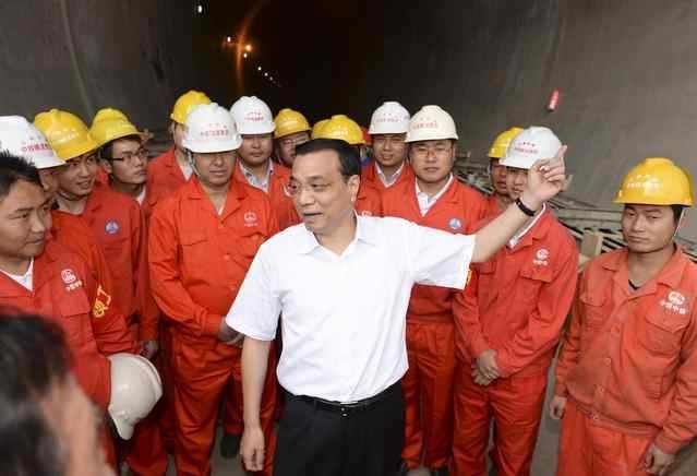 Premier Li Keqiang (center) talks to workers during a visit to the construction site of the Muzhailing tunnel construction site on the Lanzhou-Chongqing Railway in Dingxi, Gansu province, on Aug 18, 2013. Railway construction in the west opens the door to fortune: Premier