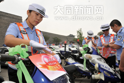 綜警隊(duì)員往車上粘送考車貼、捆綠絲帶