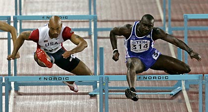 Dominique Arnold of the U.S. (L) and Ladji Doucoure of France clear hurdles during their men's 100 metres hurdles semi-final at the world athletics championships in Helsinki August 11, 2005. Doucoure finished first in the semi-final and Arnold came in second.