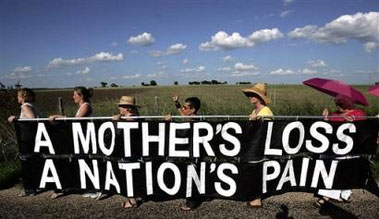 Dozens of women march with a giant letter addressed to U.S. first lady Laura Bush along a road towards the ranch of vacationing U.S. President George W. Bush in Crawford, Texas, August 18, 2005. Dozens of letters, addressed to first lady Bush appealing for her compassion to influence President Bush, were handed to White House representative Bill Burck after the women marched to a police checkpoint near the ranch. [Reuters]
