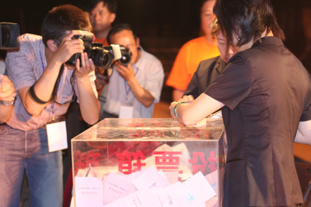 Photographers take the picture as two notary officials seal the balloting boxes after a voting on the housing demolition and compensation policy at Jiuxianqiao sub-district in Chaoyang District of Beijing, June 9, 2007. Some 3,711 families, about 57% of the 5,473 families, cast their votes on Saturday, with 2,451 votes for and 1,228 votes against the demolition and compensation plan. Thirty-two votes were invalid. [Sun Yuqing/y3k9.com]