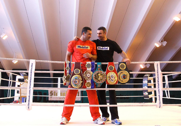 Ukranian heavyweight boxers Vladimir (L) and his brother Vitali Klitschko pose with their world championship titles belts during a photo call at their training camp in Austria. Mighty brothers show off trophy before fight