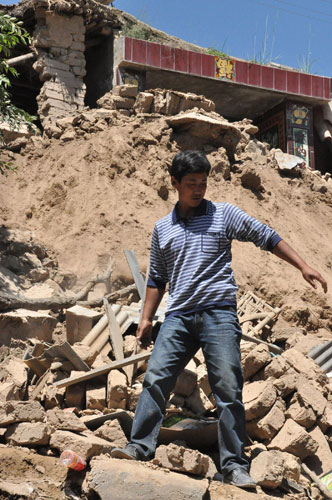 A man stands on the debris of collapsed houses in Majiagou village, Minxian county, July 22, 2013. Images from deadly quake zone