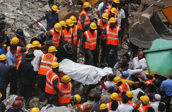 Rescue workers recover a body from the debris at the site of a collapsed residential building in central Mumbai June 11, 2013. Mumbai building collapse kills 5